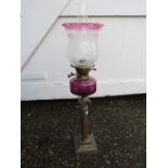 Oil lamp with cranberry coloured glass font, tulip shade and brass base