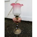 Oil lamp with cranberry coloured glass font and brass base