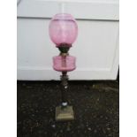 Oil lamp with brass base cranberry coloured font and globe shade