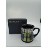 Moorcroft pottery mug in the Violet pattern (purple and white), of waisted form, designed by Sally