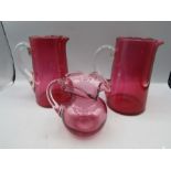 A pair of Victorian cranberry glass jugs and a small cranberry jug
