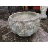 A concrete planter encircled with faces 11" high