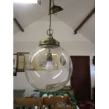 A large globe ceiling light with brass fixings.