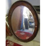 An oval wooden framed bevelled mirror