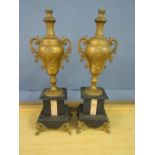 A pair of gilt urns with marble bases
