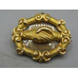 A yellow metal mourning brooch with clasping hands pattern. It bears no hallmarks but the vendor had