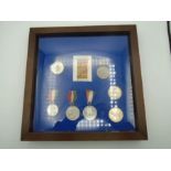 box frame with medals inside of coronations from Queen Victoria to Queen Elizabeth lI