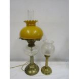 A converted oil lamp with amber coloured globe along with a candle lamp