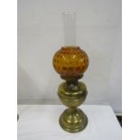 An oil lamp with amber coloured globe