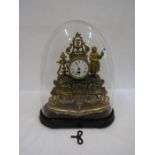 A French brass ornate clock in a glass dome with key 44cm tall from feet to top