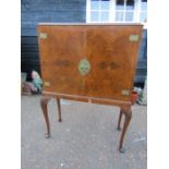 A Burr walnut cocktail cabinet on Queen Anne legs with original interior and accessories