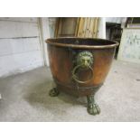 A large copper log basket with lion claw feet and lions heads