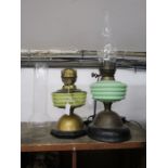 A yellow and a green glass brass based oil lamp
