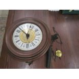 A circular wood framed wall clock with single weight , key and pendulum