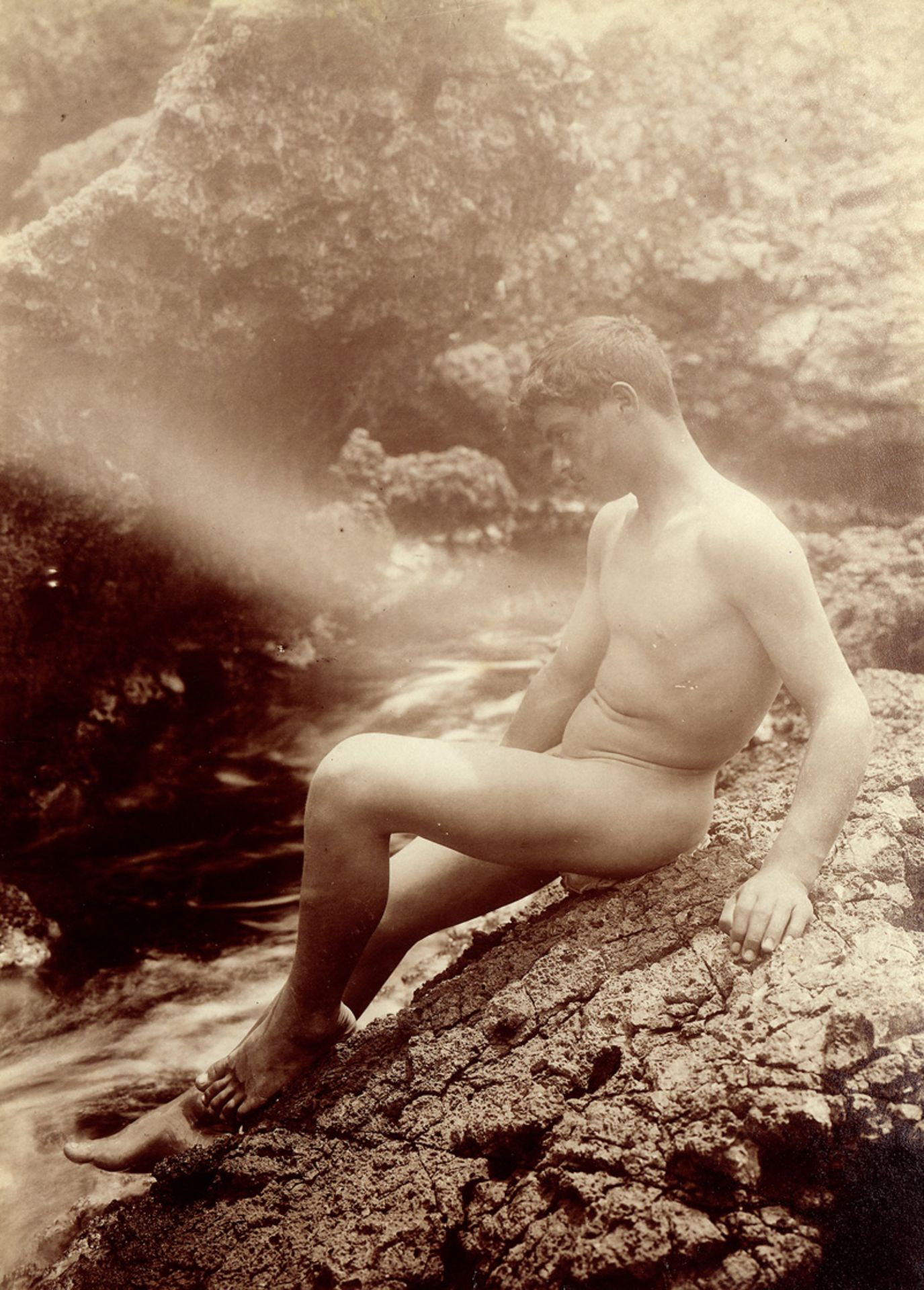 Gloeden, Wilhelm von: Male nude on rocks by the sea