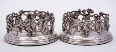 A pair of late Victorian / Edwardian plated wine coasters: with grape and vine leaf galleried sides,