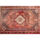 An Iranian Kashgai rug:, the brick red field with a central ivory octagonal medallion,