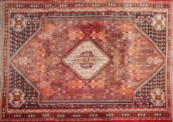 An Iranian Kashgai rug:, the brick red field with a central ivory octagonal medallion,