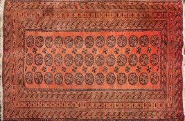 An Afghan rug:, of Turkoman design, the rose field with three rows of quartered serrated medallions,