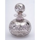 A Continental clear glass and silver overlay scent bottle and stopper: of ovoid form with foliate