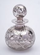 A Continental clear glass and silver overlay scent bottle and stopper: of ovoid form with foliate