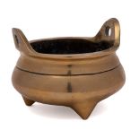A Chinese bronze tripod censer: of squat circular form with loop handles to the rim,