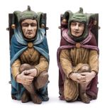 A pair of polychrome carved wood figural corbels of crouching jesters: in traditional costume,