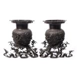 A pair of Chinese bronze vases and stands: each of ovoid form with cylindrical neck and lotus