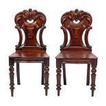 A pair of Victorian carved mahogany hall chairs:,