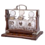 Betjeman's patent oak and plate mounted tantalus: containing three clear glass decanters and