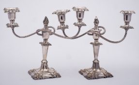 A pair of plated twin-branch candelabra: with urn-shaped sconces on swept and reeded branches,