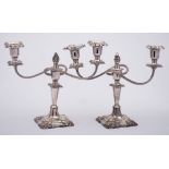 A pair of plated twin-branch candelabra: with urn-shaped sconces on swept and reeded branches,