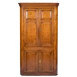 A late 18th Century oak standing corner cupboard:, with a moulded cornice and canted angles,