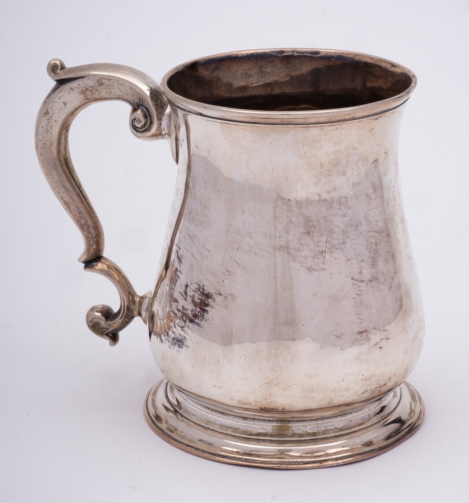 A George III silver mug, maker unknown, London, 1776: of baluster form, with capped scroll handle,