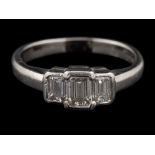 A platinum diamond three stone ring,: the central rectangular cut diamond estimated to weigh 0.