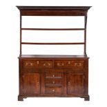 An 18th Century oak dresser:, the shelved superstructure with a moulded cornice,