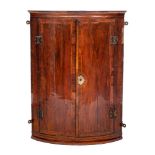 An 18th Century walnut bow-fronted hanging corner cupboard:, with a moulded cornice,