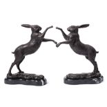 A pair of bronze fighting hares: rearing on hind legs mounted on naturalistic bases and polished