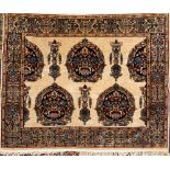 A Kashmir rug:, the ivory field with indigo ogee medallions with urns of palmettes and leaves,