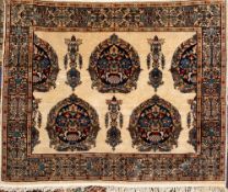 A Kashmir rug:, the ivory field with indigo ogee medallions with urns of palmettes and leaves,