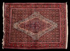 A Senneh rug:, the indigo field with a central ivory bordered stepped lozenge medallion,