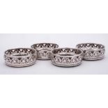 A set of four silver plated wine coasters: of circular outline with pierced scroll and foliate