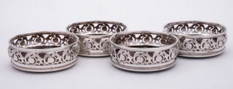 A set of four silver plated wine coasters: of circular outline with pierced scroll and foliate