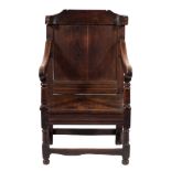 A 17th Century and later oak open armchair:, the panelled back with shaped and curved top rail,