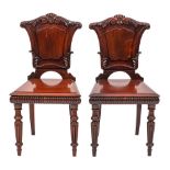 A pair of William IV carved mahogany hall chairs:,