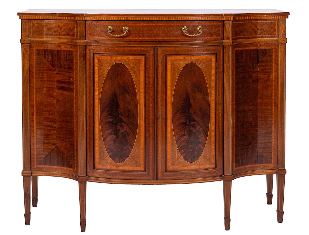 By Maple & Co Ltd An Edwardian mahogany and inlaid serpentine fronted display cabinet:,