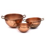 A set of three graduated copper cauldrons: with brass loop carrying handles to the sides, 27.