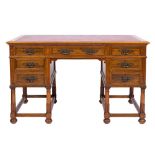 An Edwardian walnut kneehole desk:, the rectangular moulded top inset with a panel of faux leather,