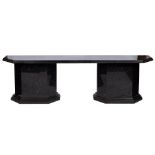 A contemporary black granite side table: the moulded chamfered top raised on end supports on