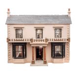 A late 19th/early 20th century double fronted dolls house: double chimney over black simulated